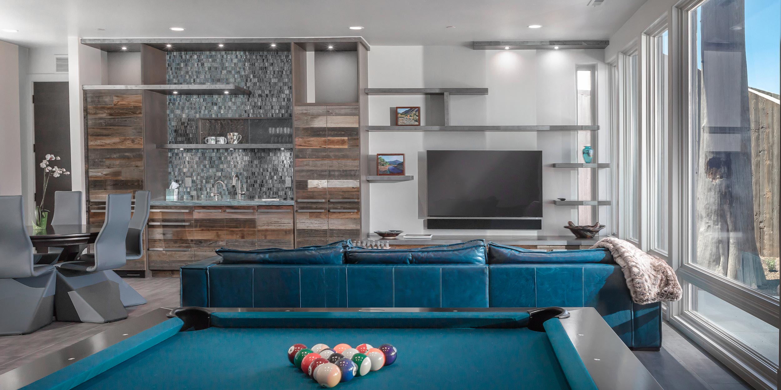 A modern entertainment space with a pool table, a large TV, and sleek shelves against a stylish backdrop.
