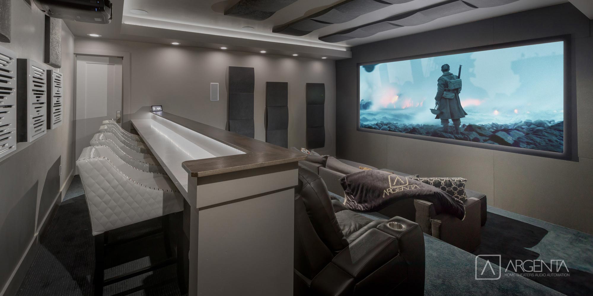 A private home theater with reclining seats, a large screen, and comfortable modern décor.