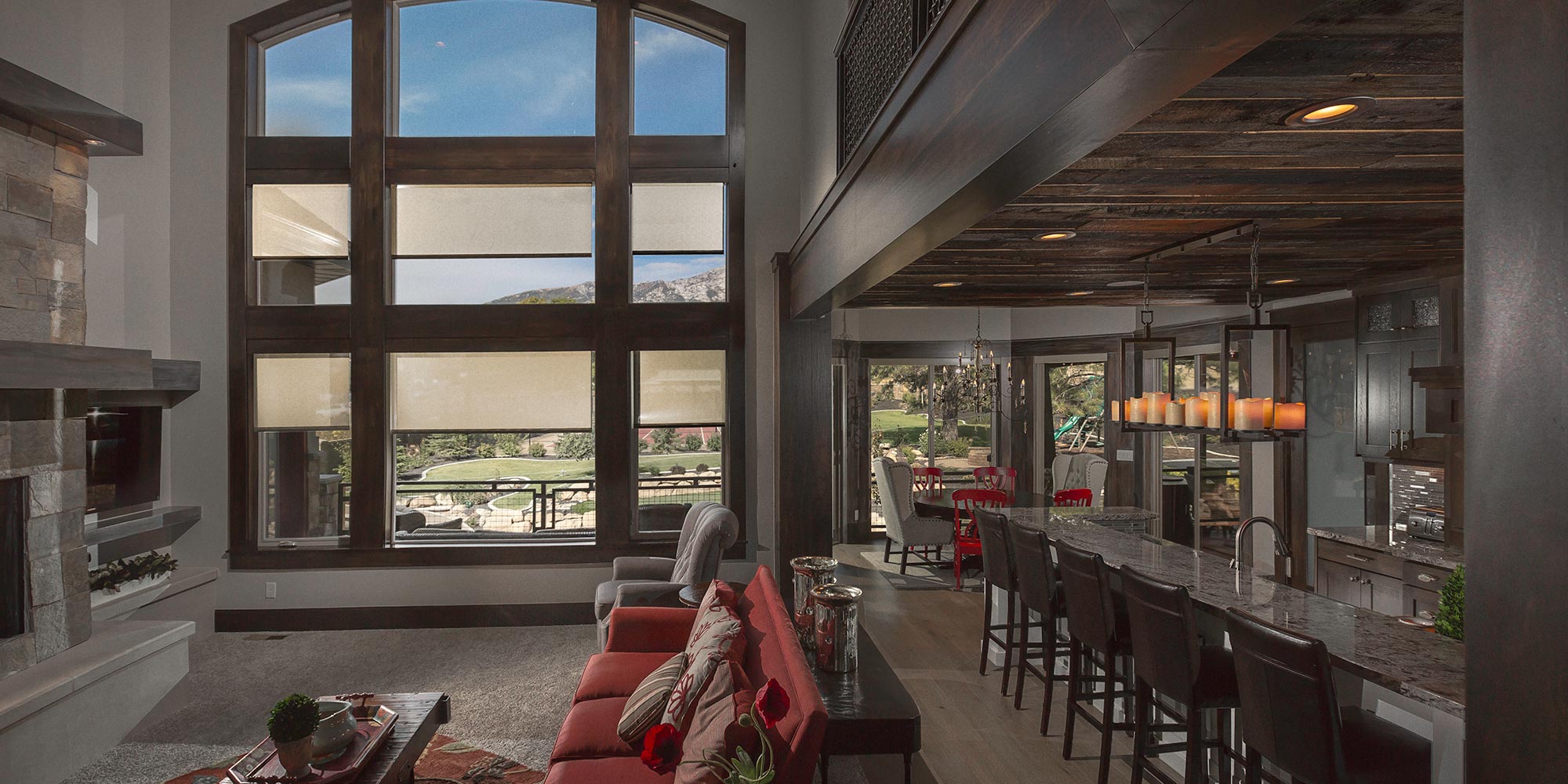 A warm and inviting living room with high ceilings, large windows, and automated window shades.