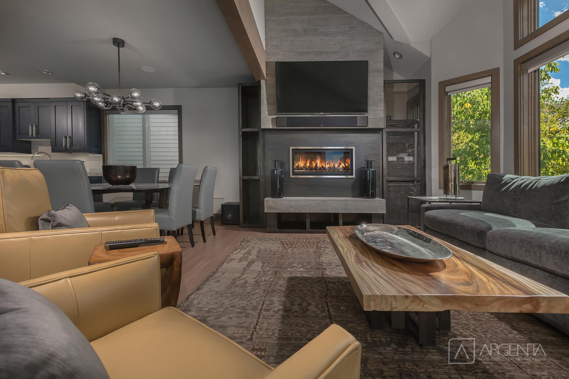 A cozy living room with a modern fireplace, elegant furniture, and natural light pouring in through large windows.