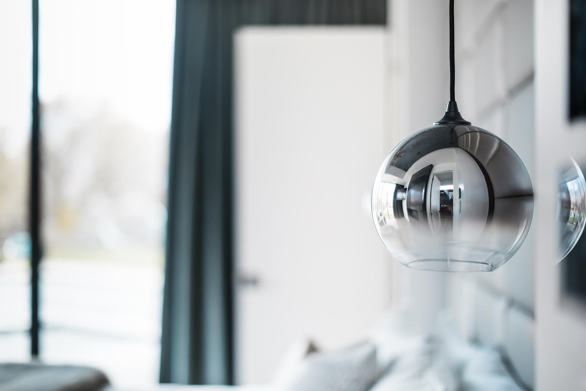 A close-up of a modern pendant light with a reflective glass design in a softly lit interior.