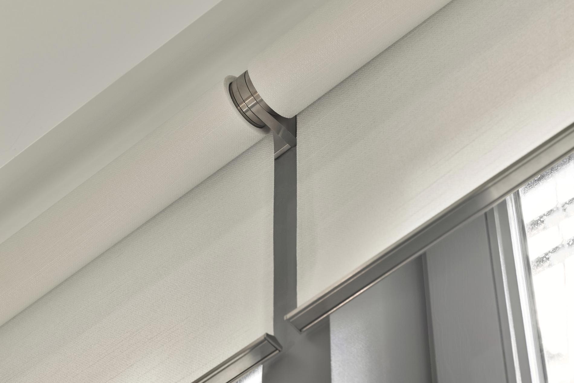 A detailed view of motorized window treatments with sleek, modern hardware in a bright, minimalist setting.