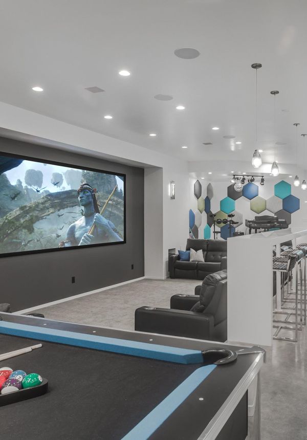 Bright modern entertainment room with large projector screen, hexagonal wall panels, and a pool table