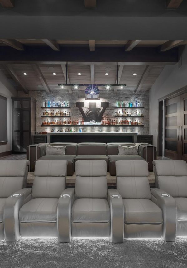 Luxury home theater with gray recliners, dramatic lighting, and backlit liquor bar