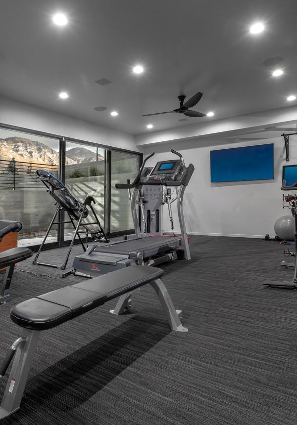 Home gym with black flooring, cardio equipment, and full-height glass windows overlooking mountains