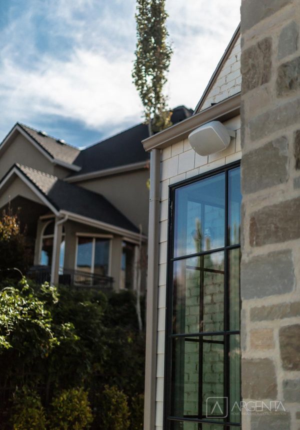 Close-up of exterior smart speaker mounted on modern stone and shingle home